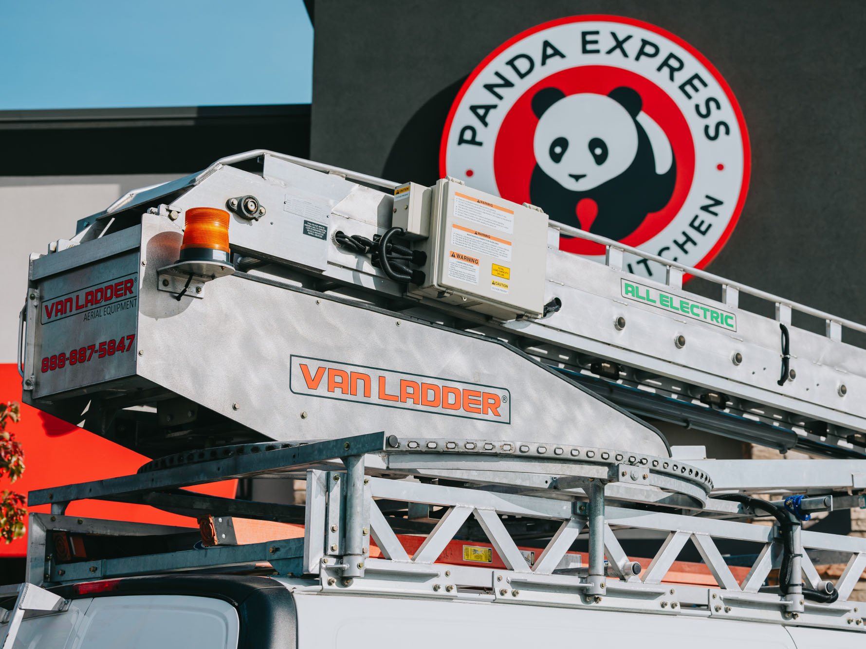 Van Ladder bucket truck close-up with the Panda Express logo sign in the background — Rick Signs national brand client work in Chicago
