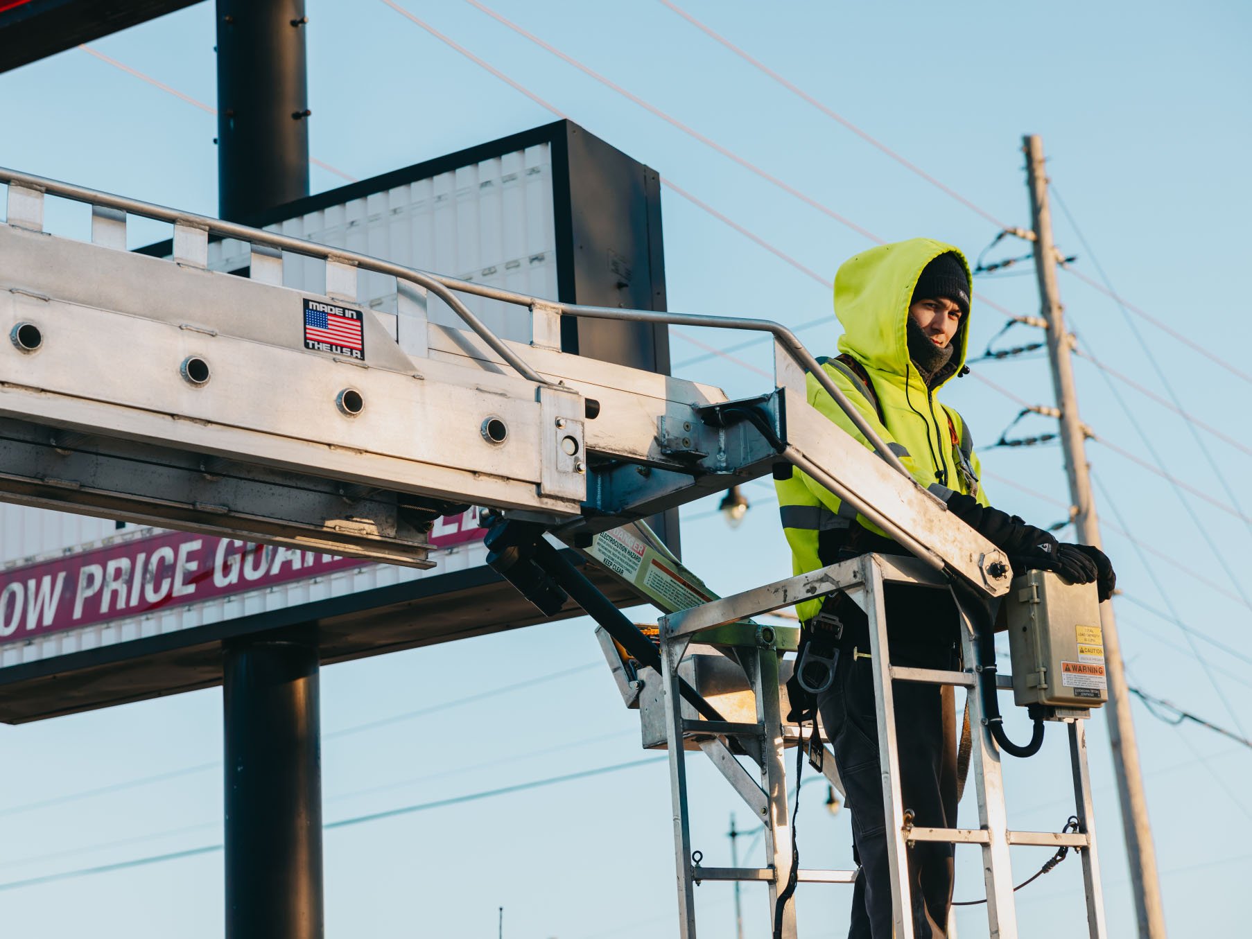 Rick Signs technician in cold-weather gear operating the bucket truck during a winter pole sign repair in Chicago
