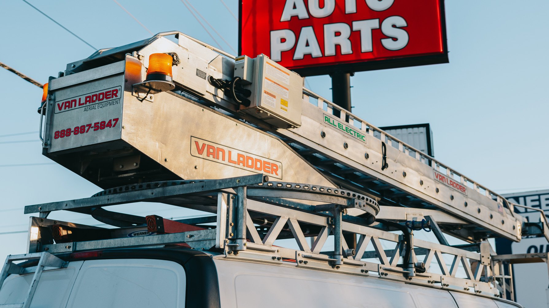Van Ladder bucket truck positioned beneath an illuminated Auto Parts pole sign during a Rick Signs service call in Chicago