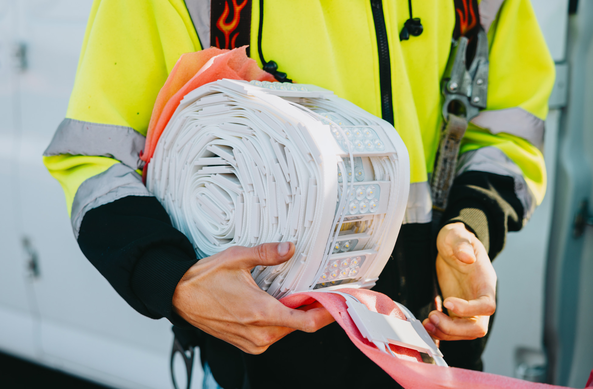 Rick Signs technician holding a rolled LED module strip used to retrofit and repair channel letter and cabinet signs