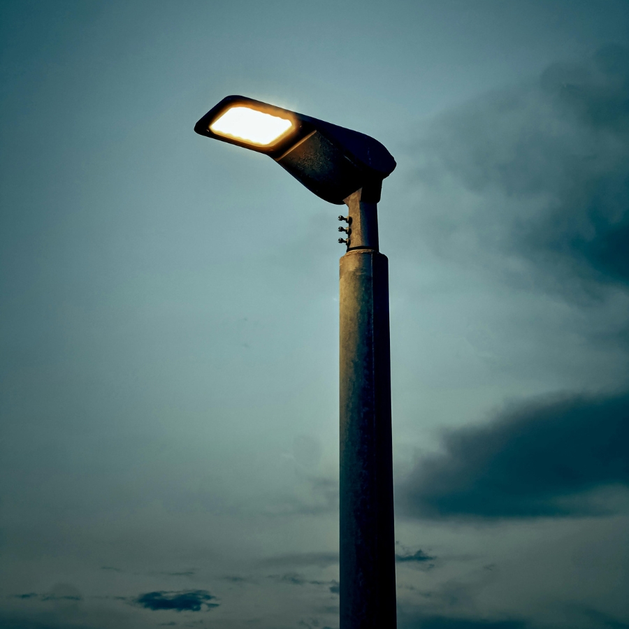 Parking lot pole light glowing against a Chicago dusk sky — exterior commercial lighting and pole light repair by Rick Signs