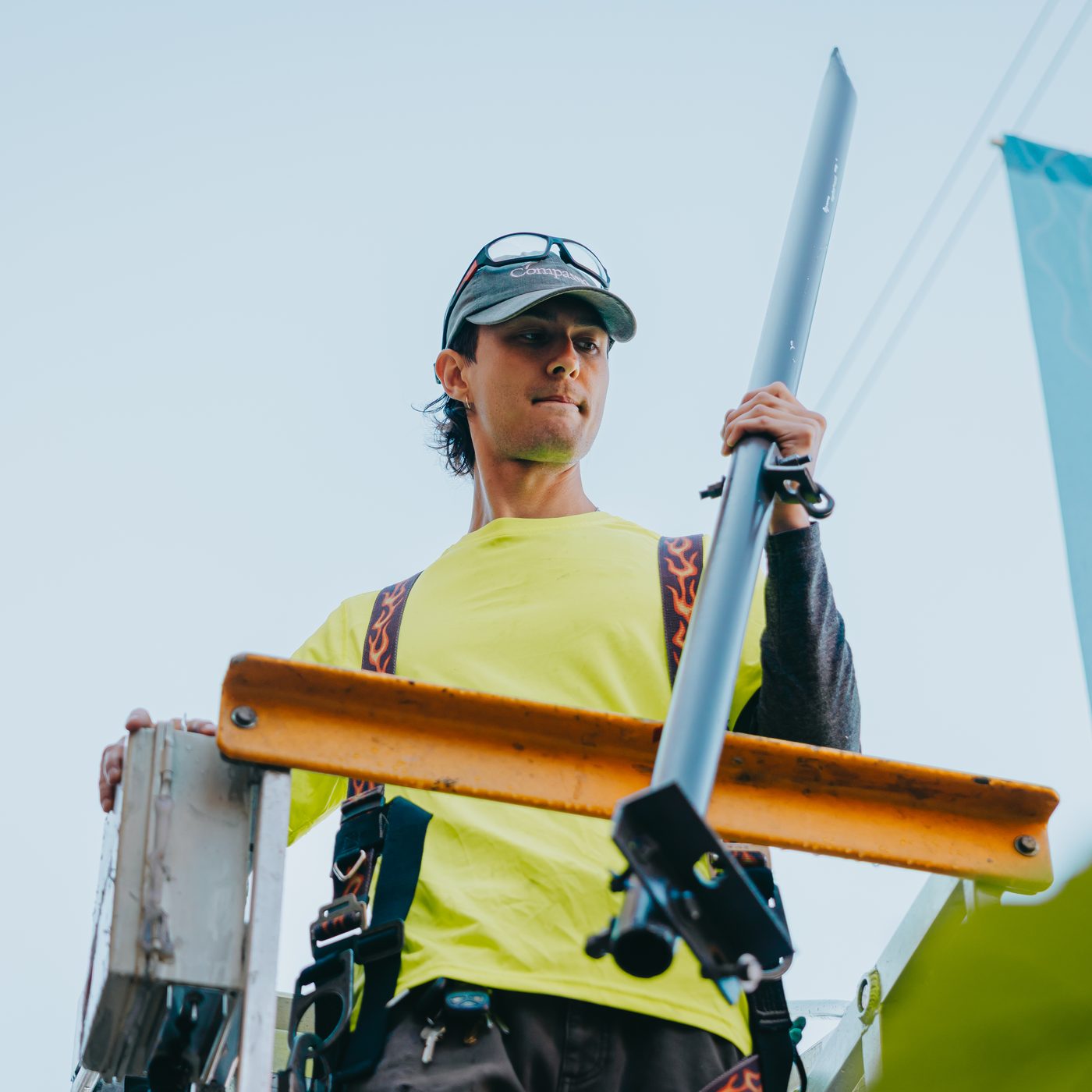 Rick Signs technician on a lift holding the steel mounting rail and level before setting a projecting sign bracket in Chicago