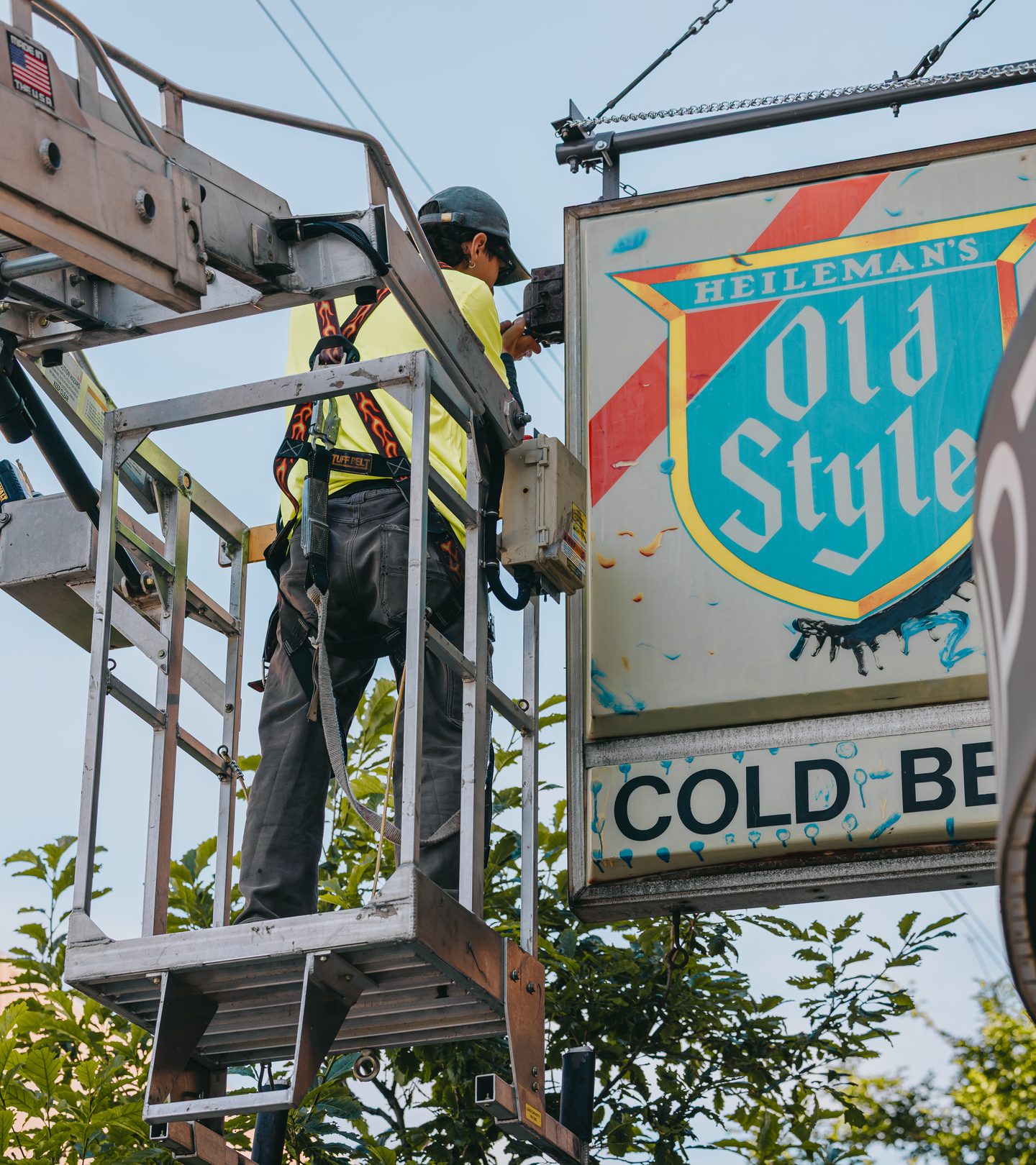 Rick Signs technician on a bucket truck lift alongside the newly hung Old Style Cold Beer projecting sign at Empty Bottle