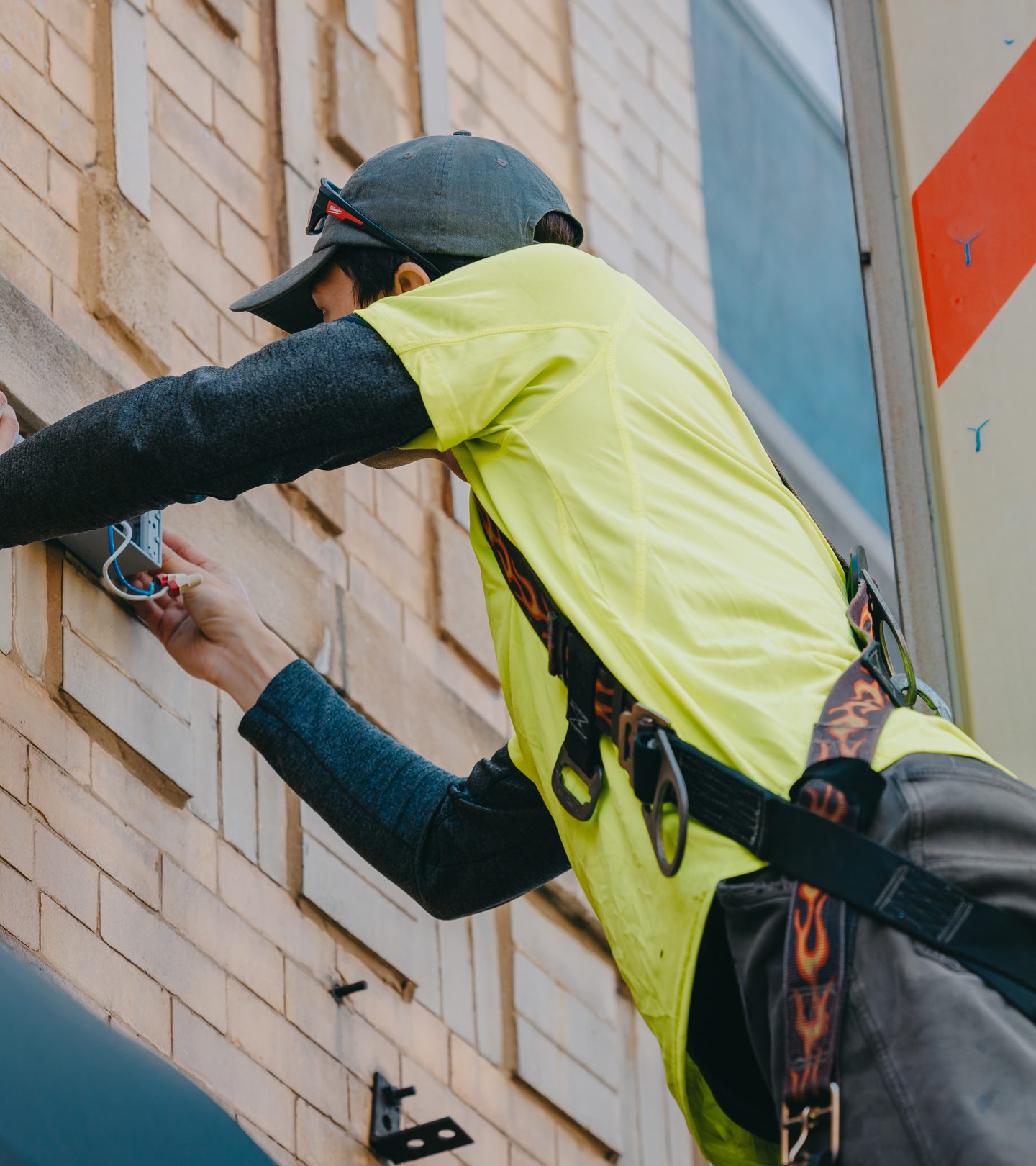 Technician setting masonry anchors into century-old Chicago brick for a projecting sign mount — Rick Signs & Repairs