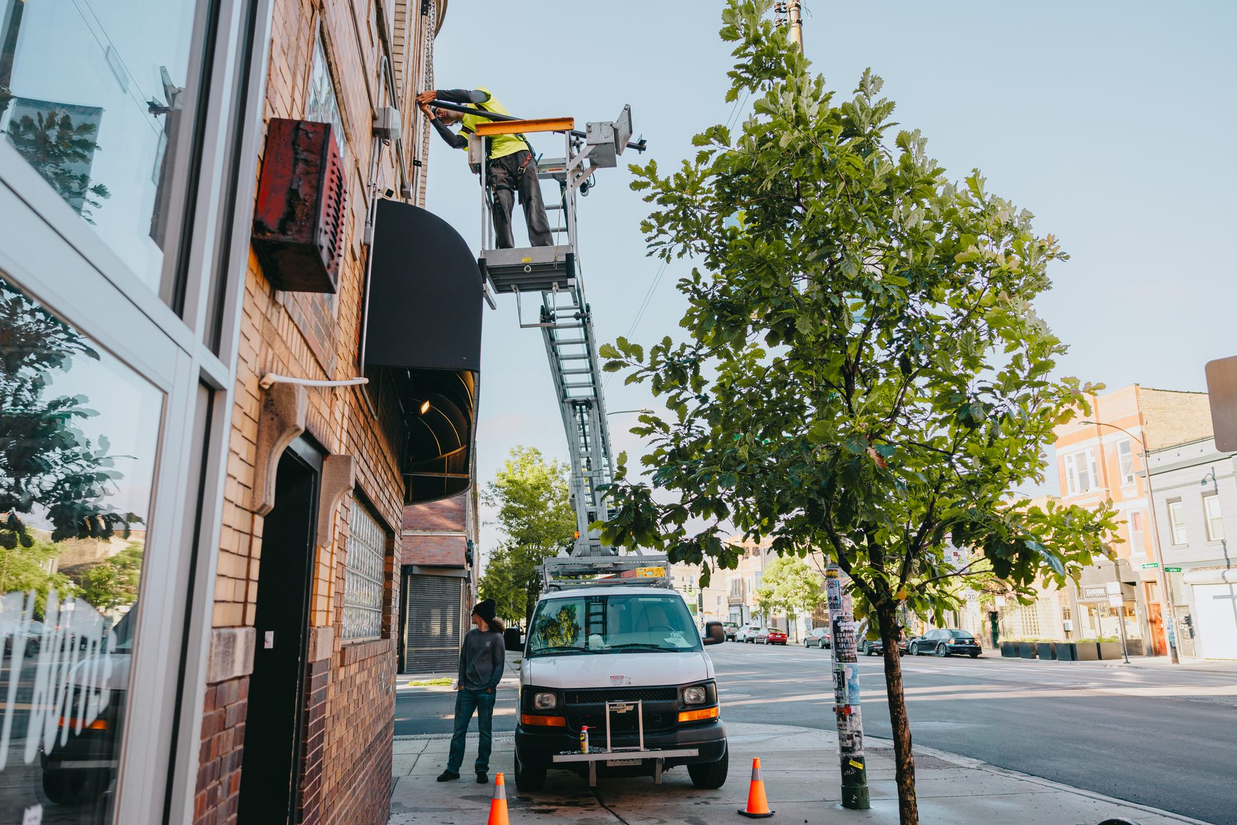 Van Ladder bucket truck extended to the second story during a projecting sign installation on a Chicago brick storefront