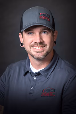 Headshot of a Midwest Erectors crew member wearing a gray company ballcap and polo, with an earring and short beard