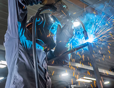 Close-up of a welder in a helmet with sparks flying during steel fabrication