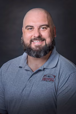 Headshot of a bald, bearded Midwest Erectors crew member wearing a gray company polo