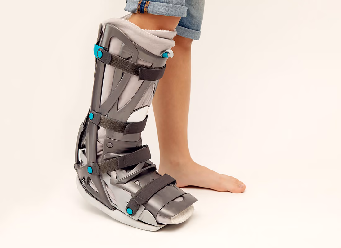Person trägt eine medizinische orthopädische Schiene am linken Bein, rechter Fuß ist barfuß.