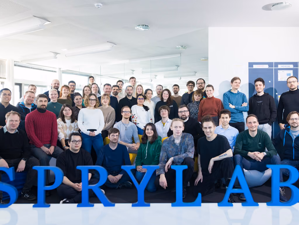 Gruppenfoto eines Teams in einem hellen Raum mit großen blauen Buchstaben vorne.