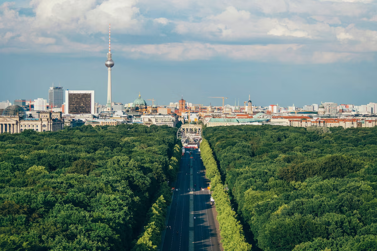 Blick auf Berlins Stadtzentrum mit dem Fernsehturm, grünen Bäumen und einem Riesenrad in der Mitte.