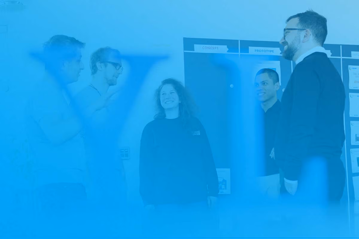 Fünf Personen in einem Büro stehen vor einem Board mit Konzept- und Prototypenphasen.
