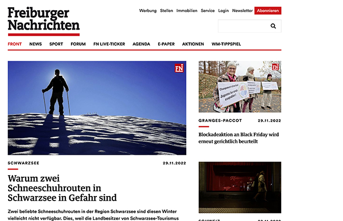 Silhouette einer Person mit Schneeschuhen auf verschneitem Hang vor blauem Himmel.