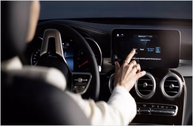 Person steuert das digitale Display in einem modernen Auto mit Touchscreen-Menü.