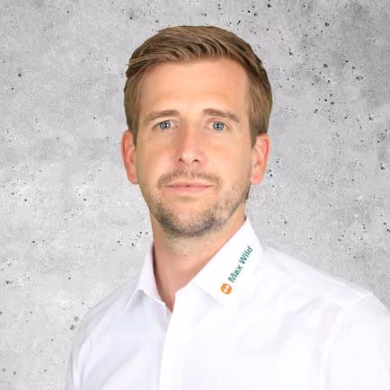 Porträt eines Mannes mit hellem Hemd vor grauem Hintergrund.