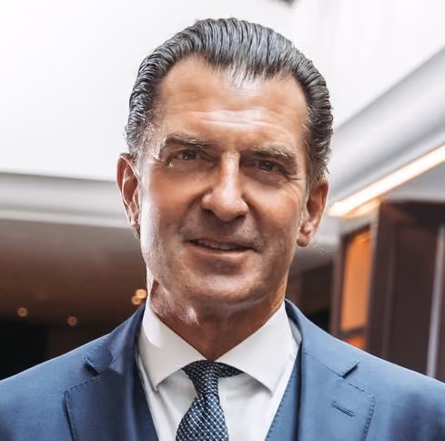 Porträt eines Mannes in blauem Anzug mit weißem Hemd und geflochtener Krawatte.