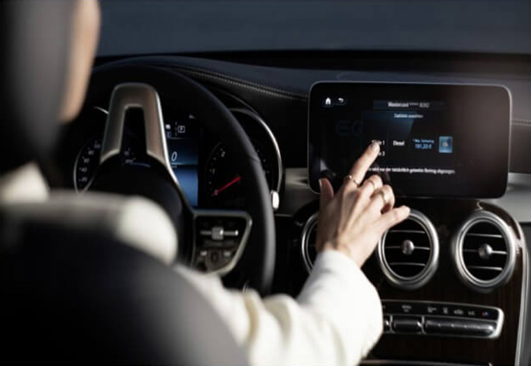 Eine Person bedient das Touchscreen-Display in einem modernen Auto am Armaturenbrett.