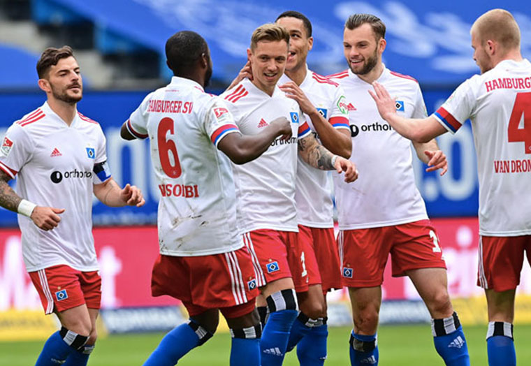 HSV-Spieler in weißen Trikots feiern auf dem Fußballfeld während eines Spiels.