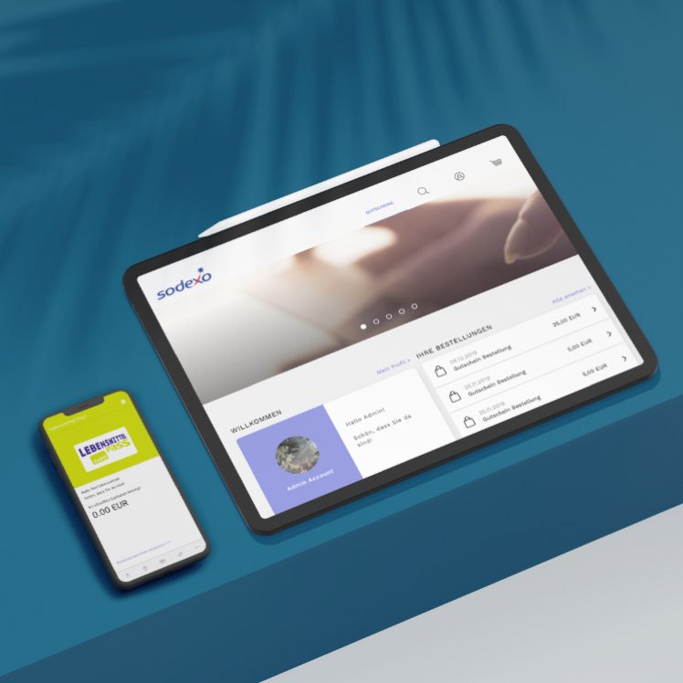 Tablet und Smartphone anzeigen die Sodexo-Plattform mit Gutscheinen und Benutzerprofil auf einem blauen Tisch.