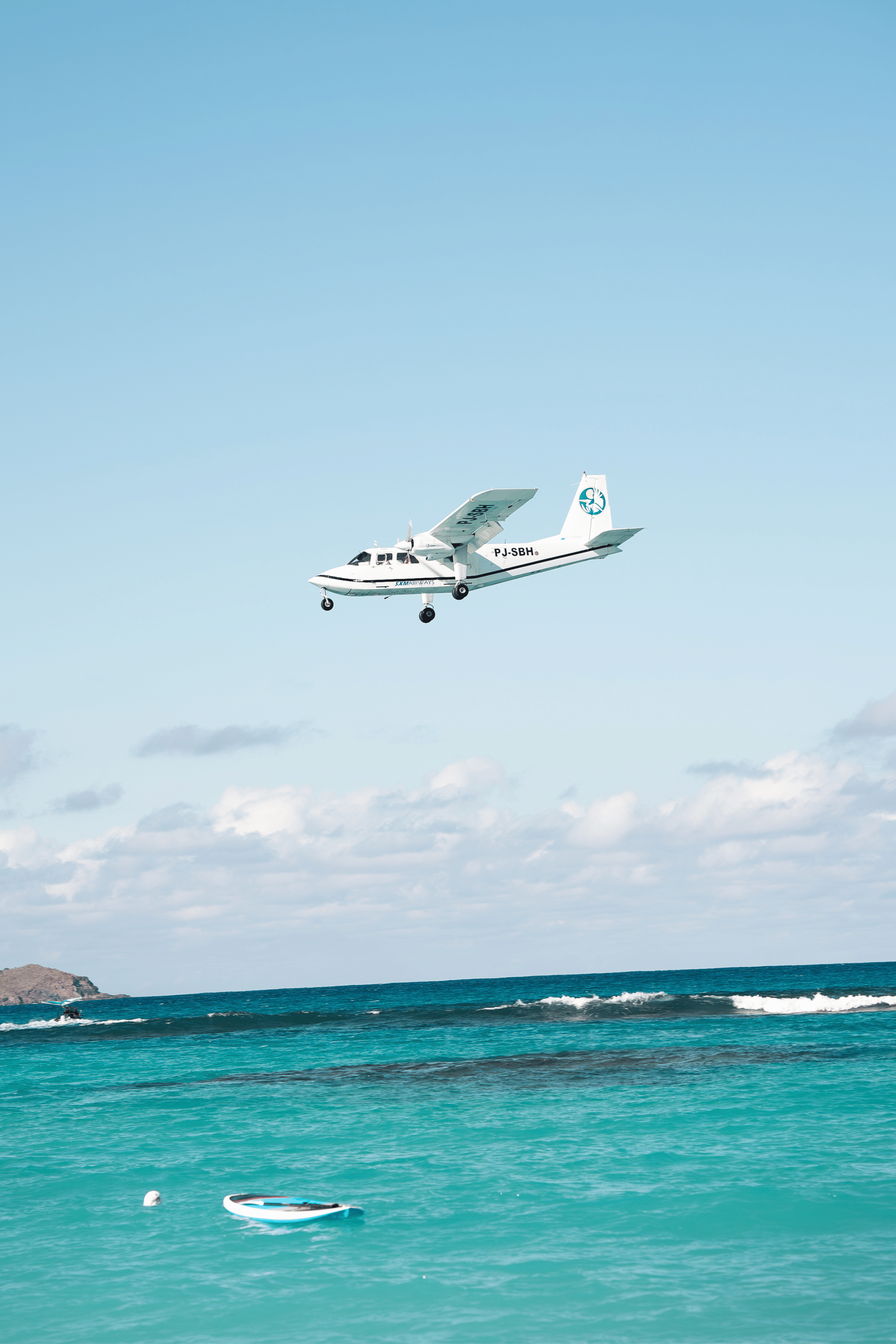 La Petite Plage St BarthFemme en maillot de bain marchant sur un chemin de plage bordé de palmiers, avec vue sur la mer turquoise en arrière-plan.