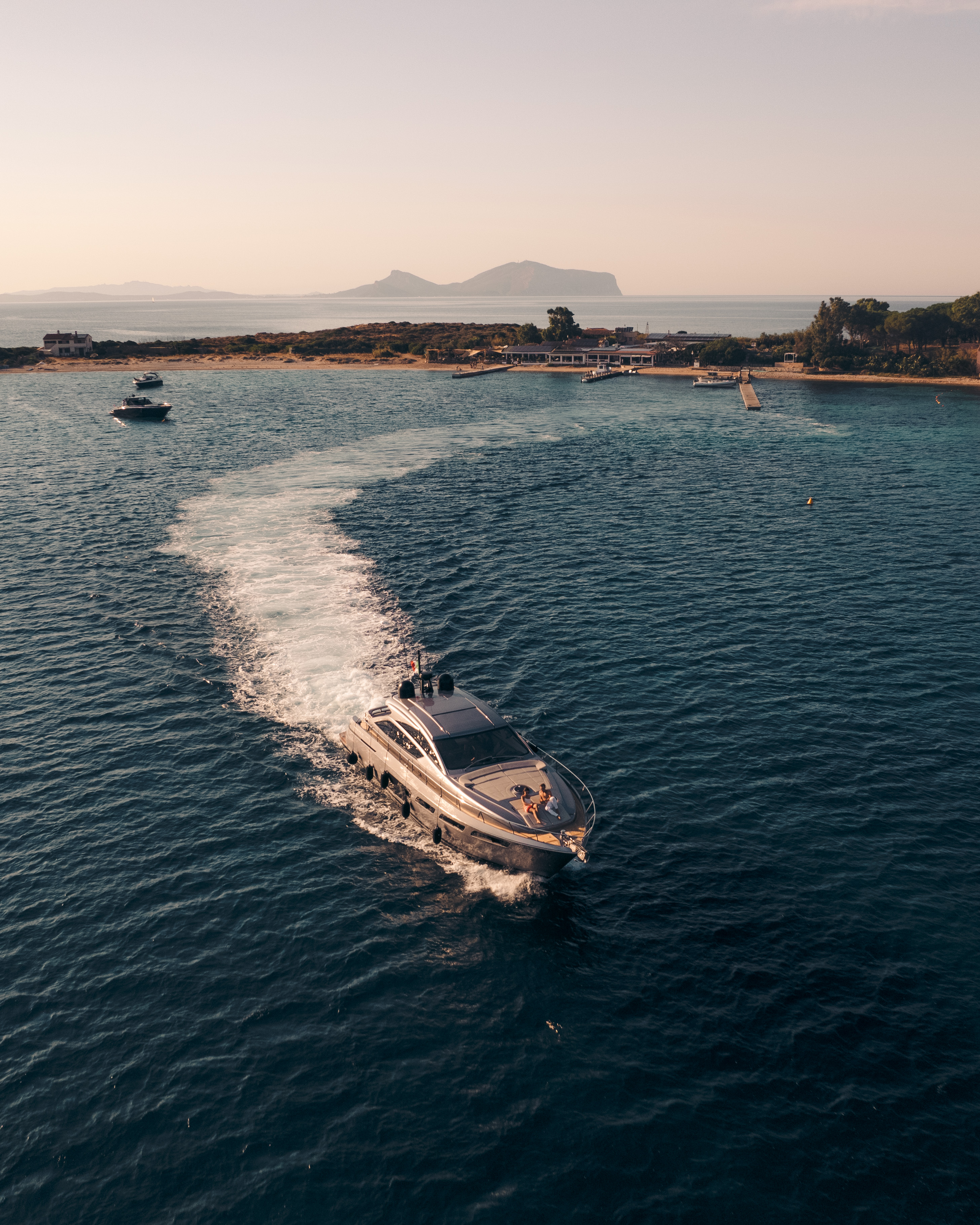 Vue aérienne d'un yacht naviguant sur la mer, laissant un large sillage blanc derrière lui.