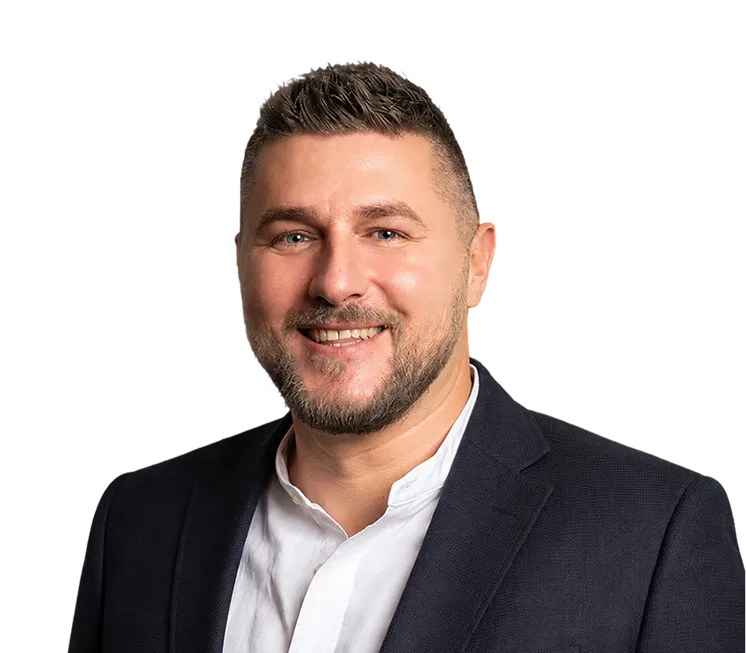 Smiling man with short hair and beard wearing a white shirt and dark blazer.