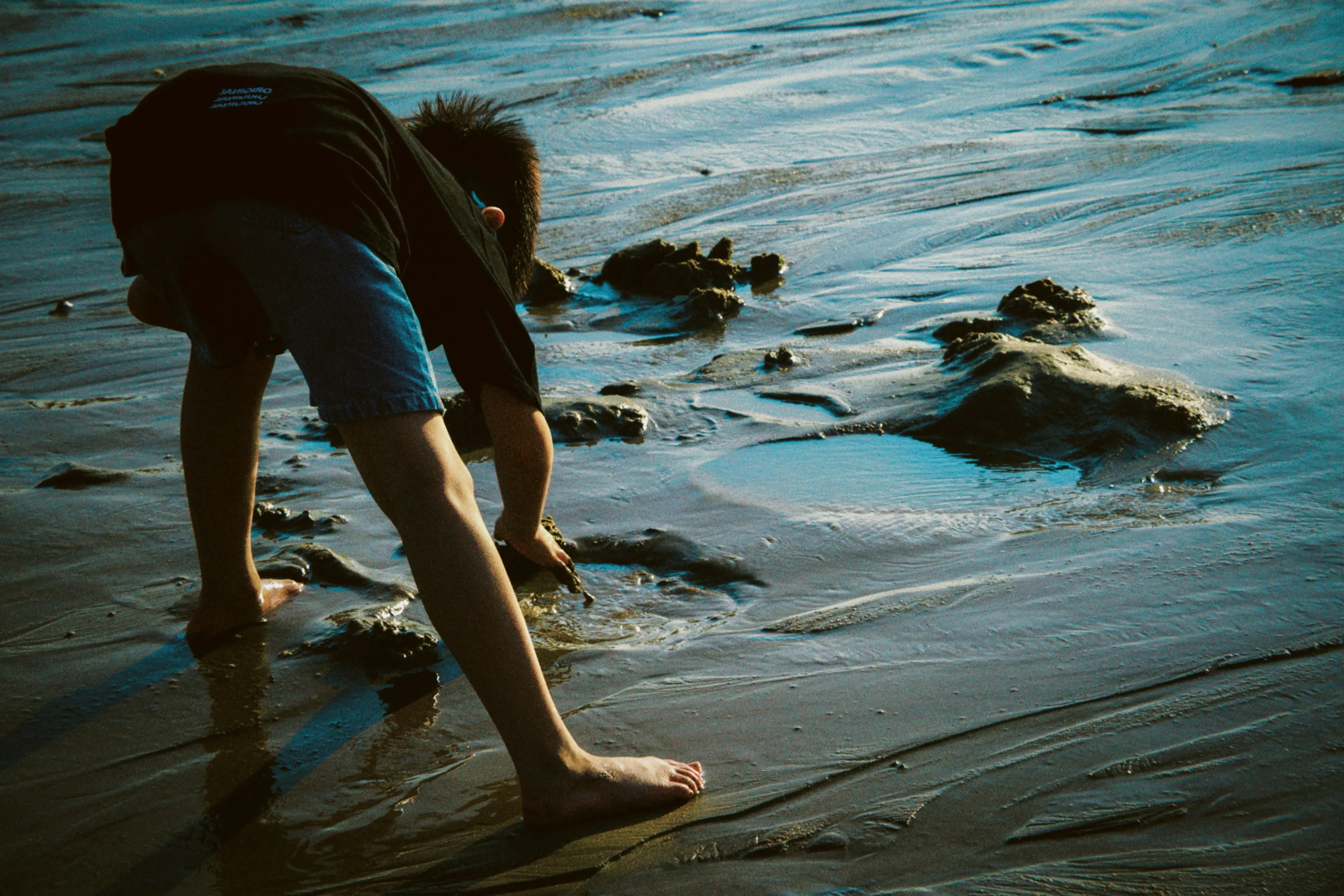 Enfant penché sur le sable mouillé au bord de la mer