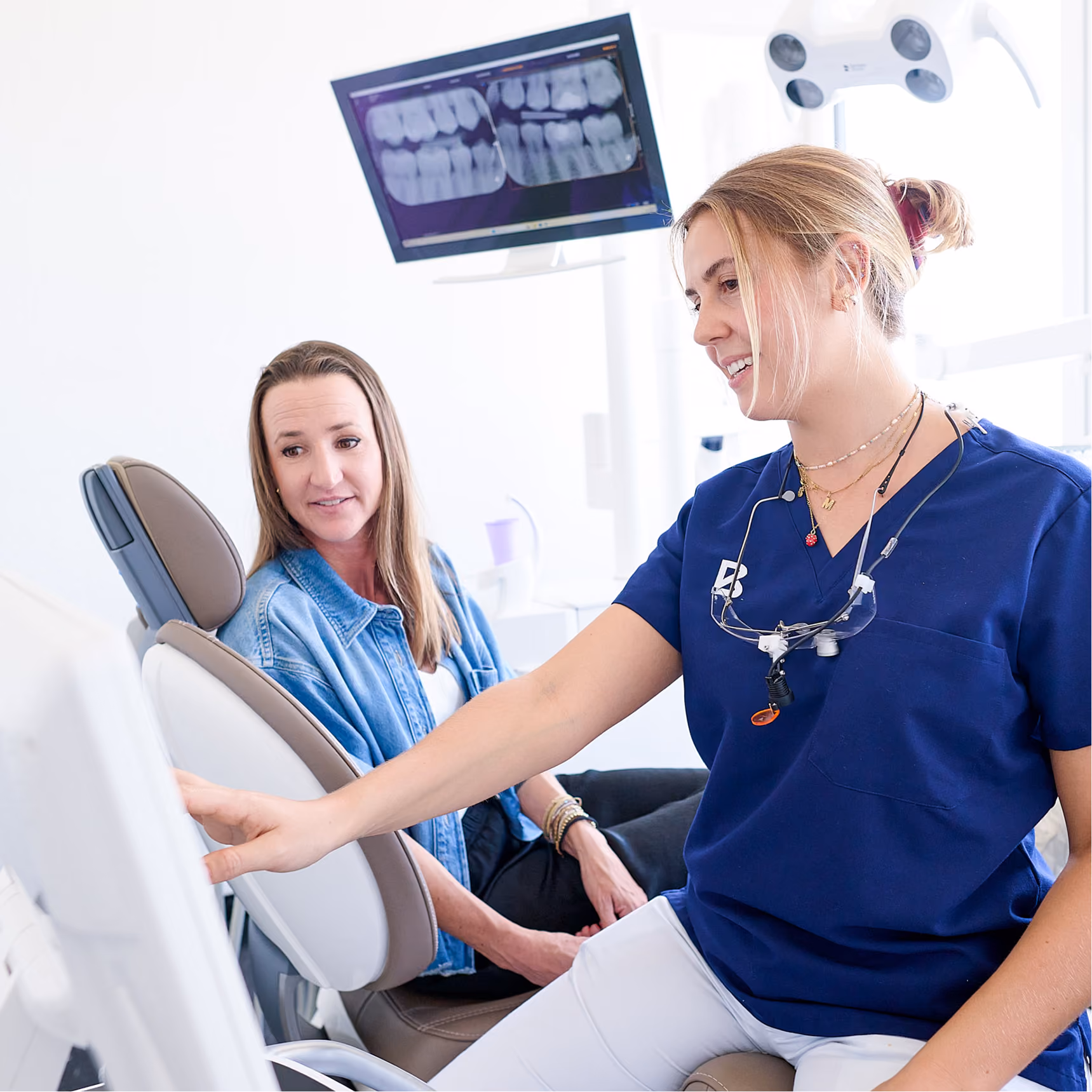 Zahnärztin erklärt Patientin digitale Röntgenbilder in der Praxis.