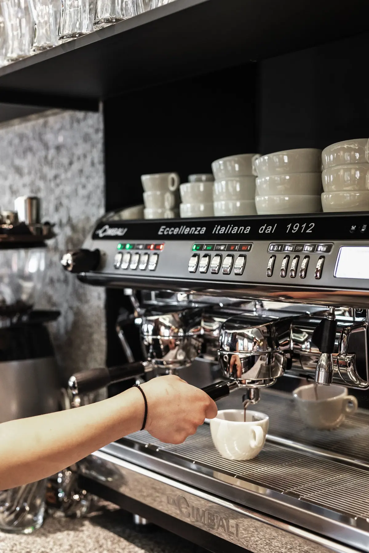 Hand bedient eine Espressomaschine, die Kaffee in eine weiße Tasse brüht.