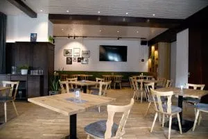 Leeres Café mit Holztischen und Stühlen, einem Fernseher und Wanddekoration.