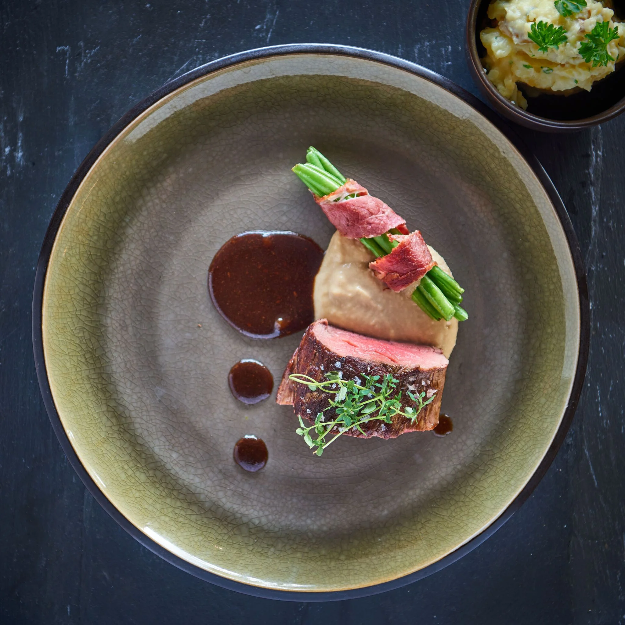 Elegant dish with caviar, herbs, and edible flowers arranged in a deep beige bowl on marble.