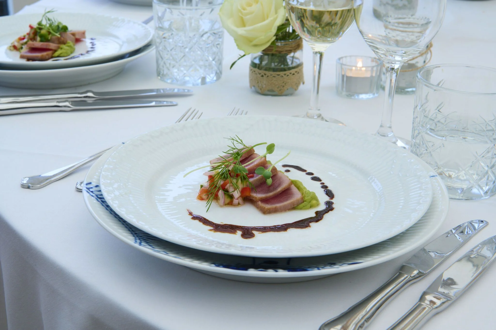 Close-up of a spoon lifting foam-covered gourmet dish with broth and garnishes in a bowl.