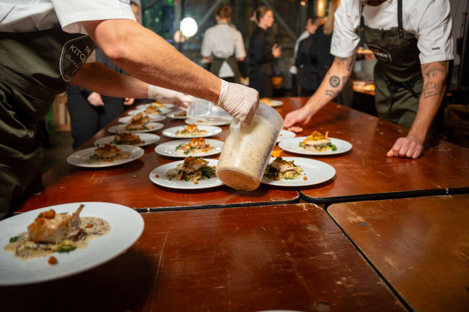 Chef slicing white truffle over creamy pasta served in a white bowl with gold rim.