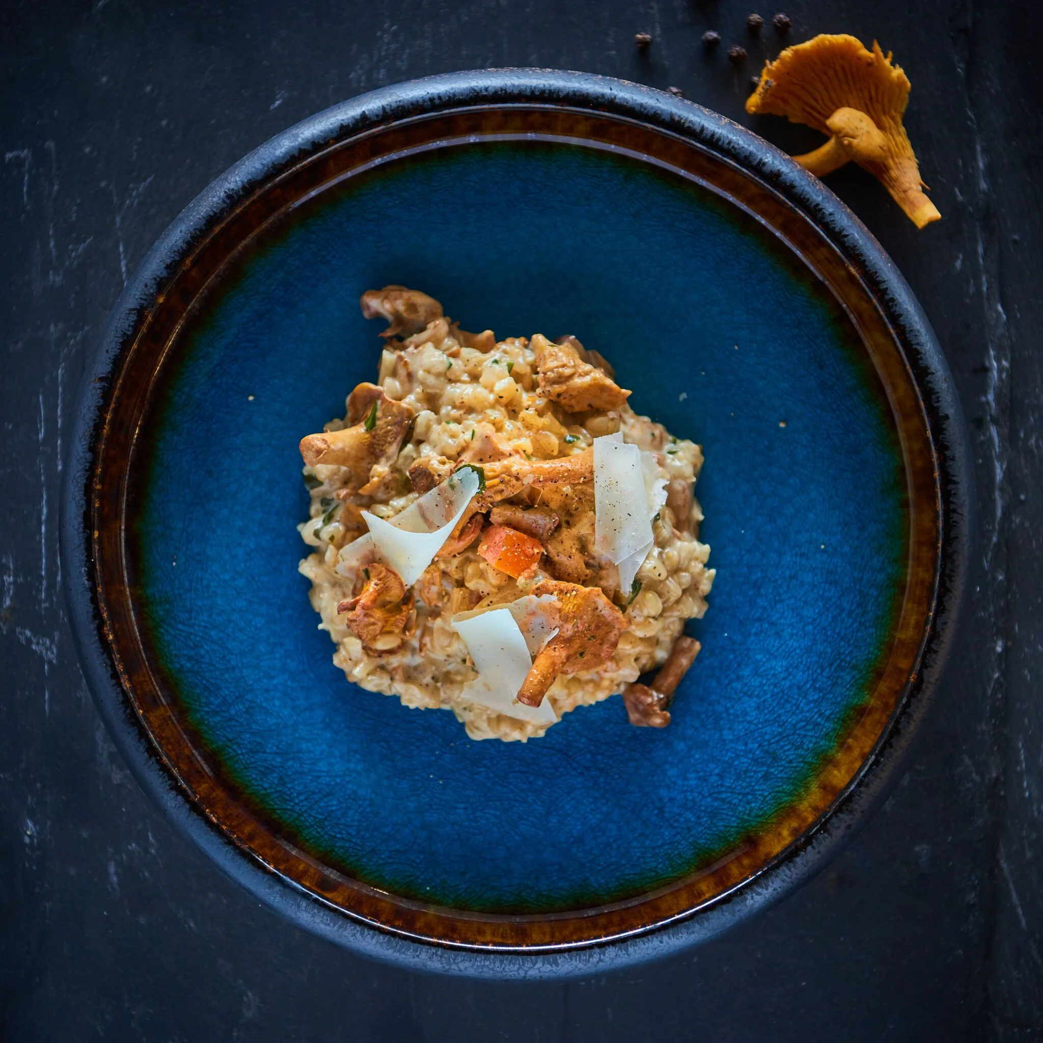Ristet risotto med kantareller og parmesan serveret i en blå skål.