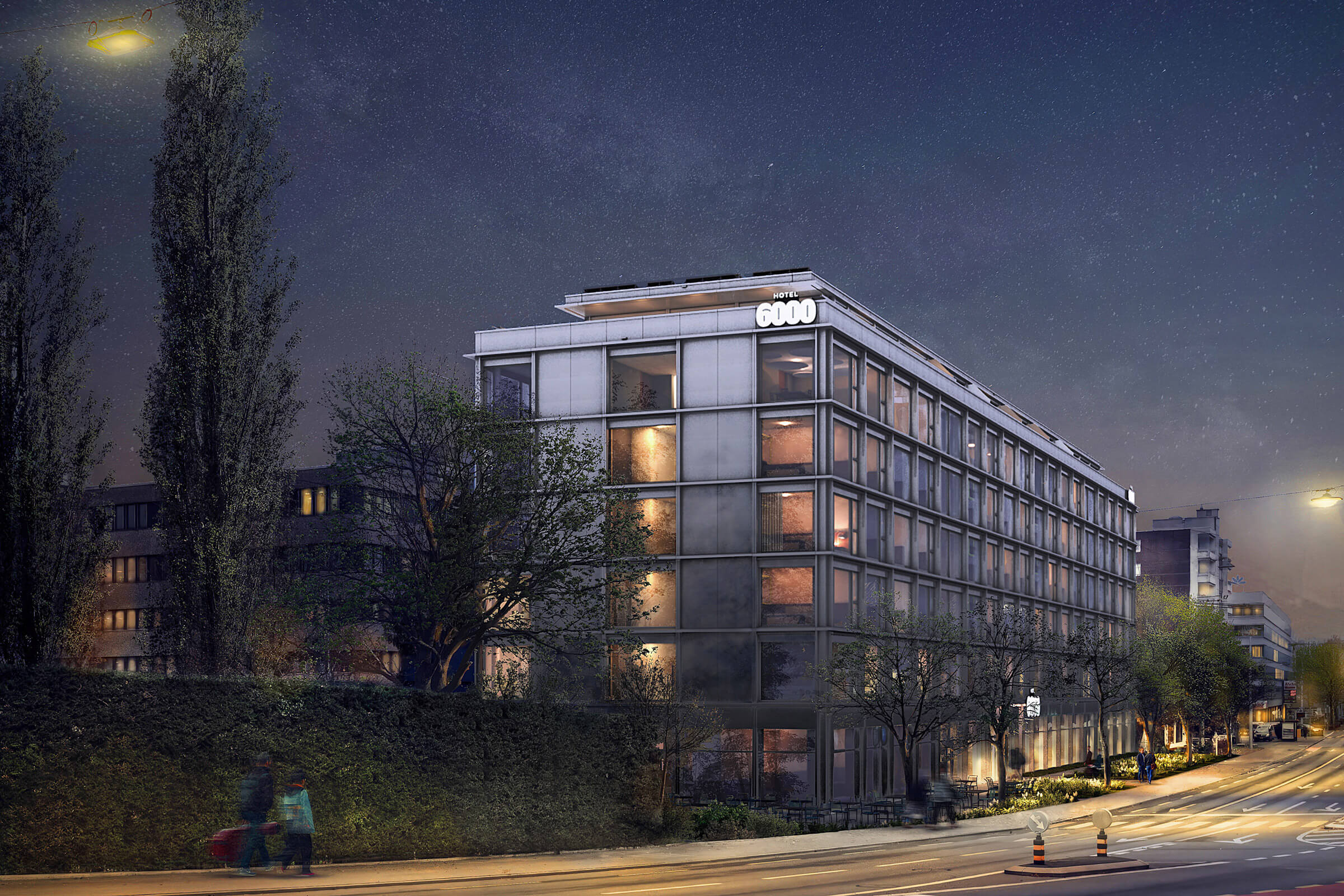 Das Hotel-6000 bei Nacht mit beleuchteten Fenstern; auf der Strasse gehen mehrere Personen.