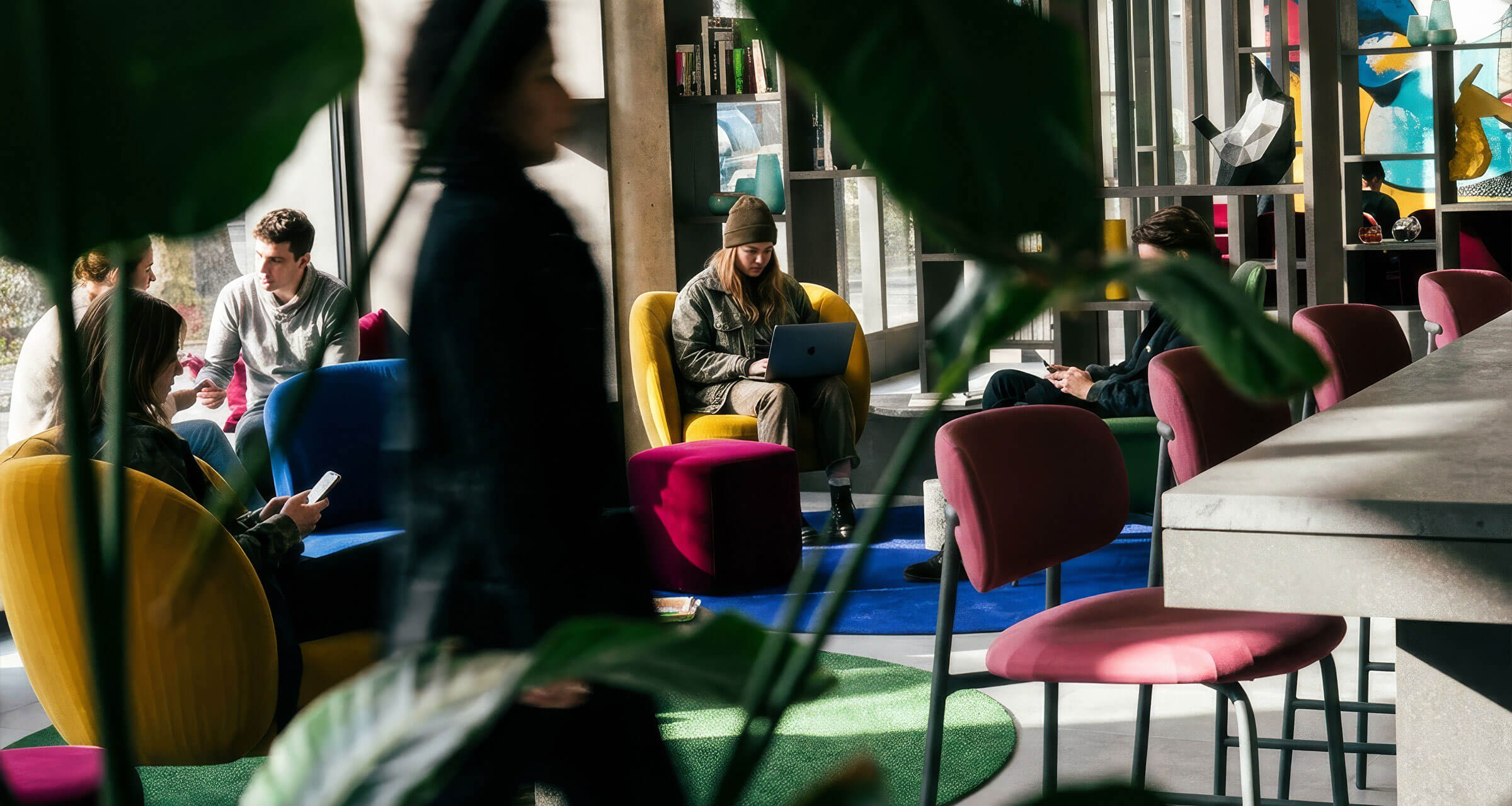 Mehrere Personen sitzen in der Lobby vom Hotel 6000 mit bunten Sesseln und natürlichem Licht.