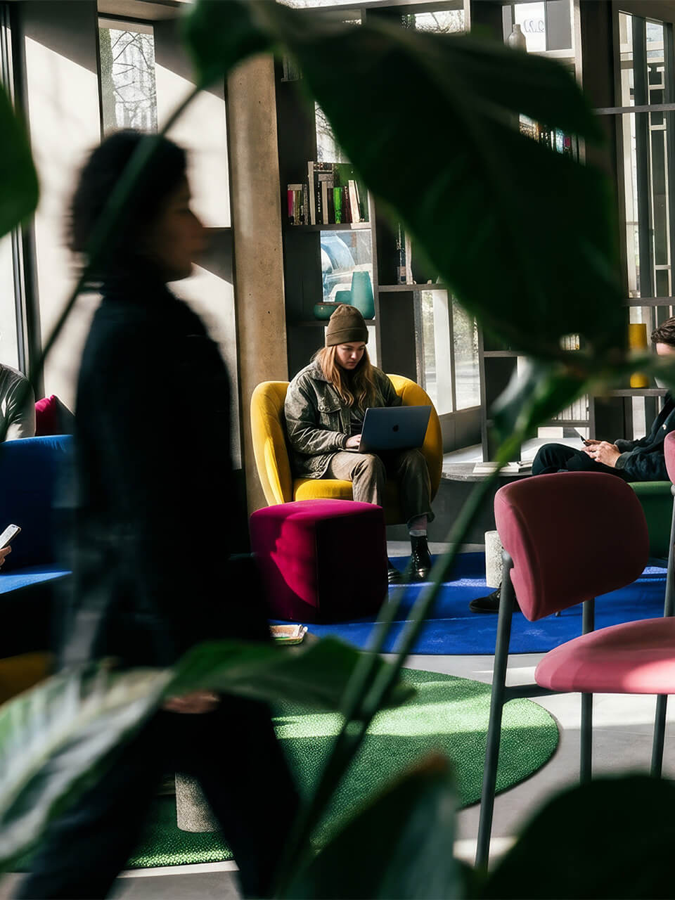 Person sitzt in gelbem Sessel im modernen Wartebereich und arbeitet am Laptop.