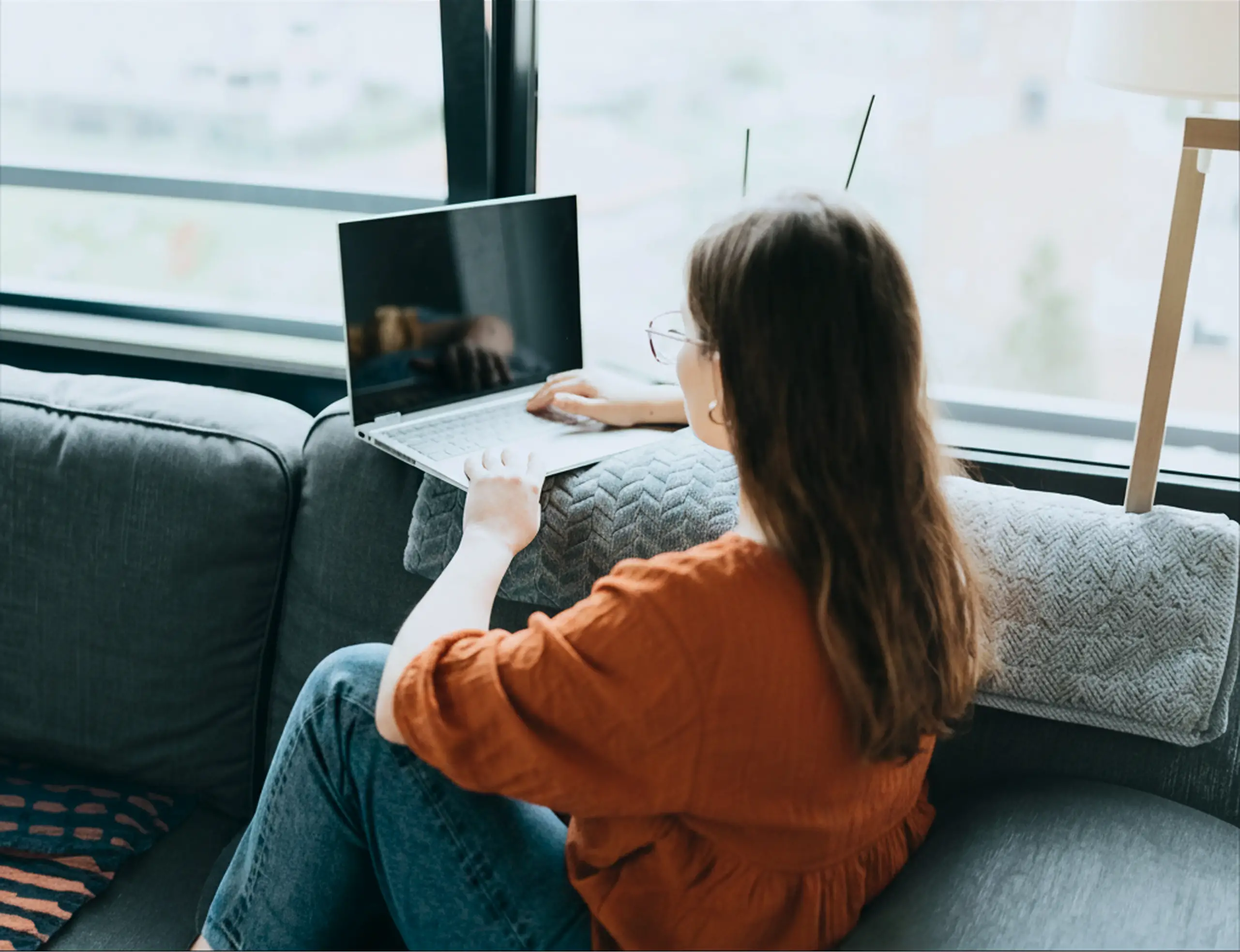 A woman sitting down while on her laptop.