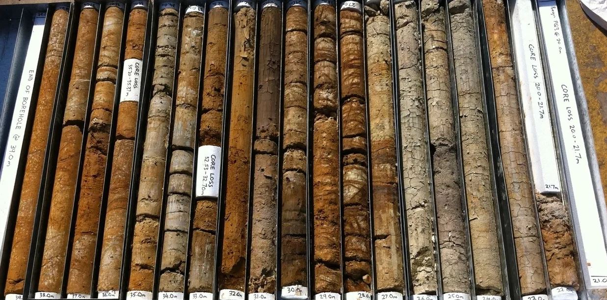 Multiple cylindrical metal molds filled with wet concrete on a concrete floor.