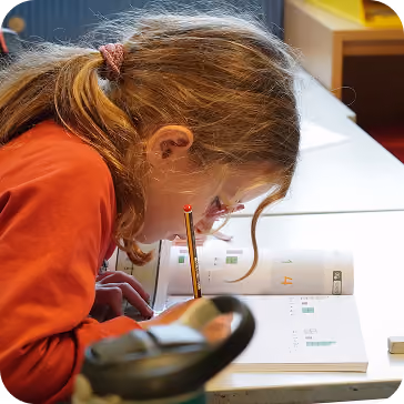 Elev på småtrinnet jobber konsentrert i en arbeidsbok
