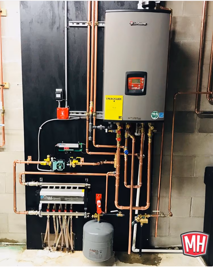 Modern Lochinvar water heater system with connected copper pipes, valves, and expansion tank mounted on wall.