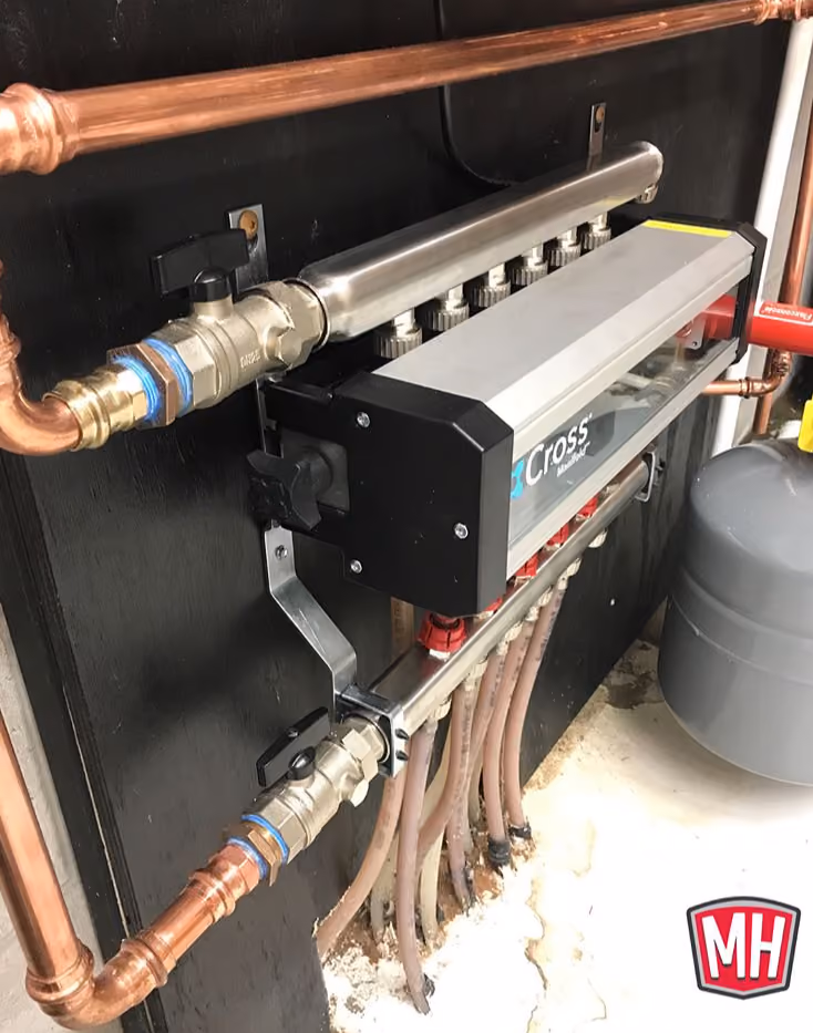 Close-up of a mechanical manifold system with copper pipes and multiple flexible tubes attached to a black panel.