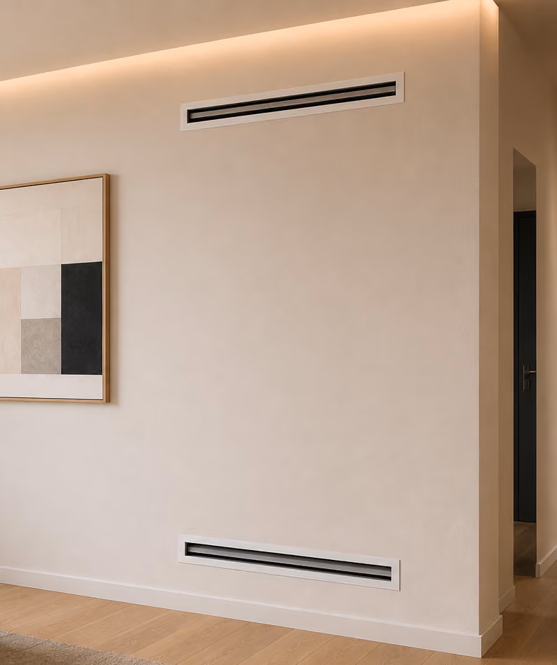 Minimalist beige wall with two rectangular air vents and part of geometric wall art on wood floor.