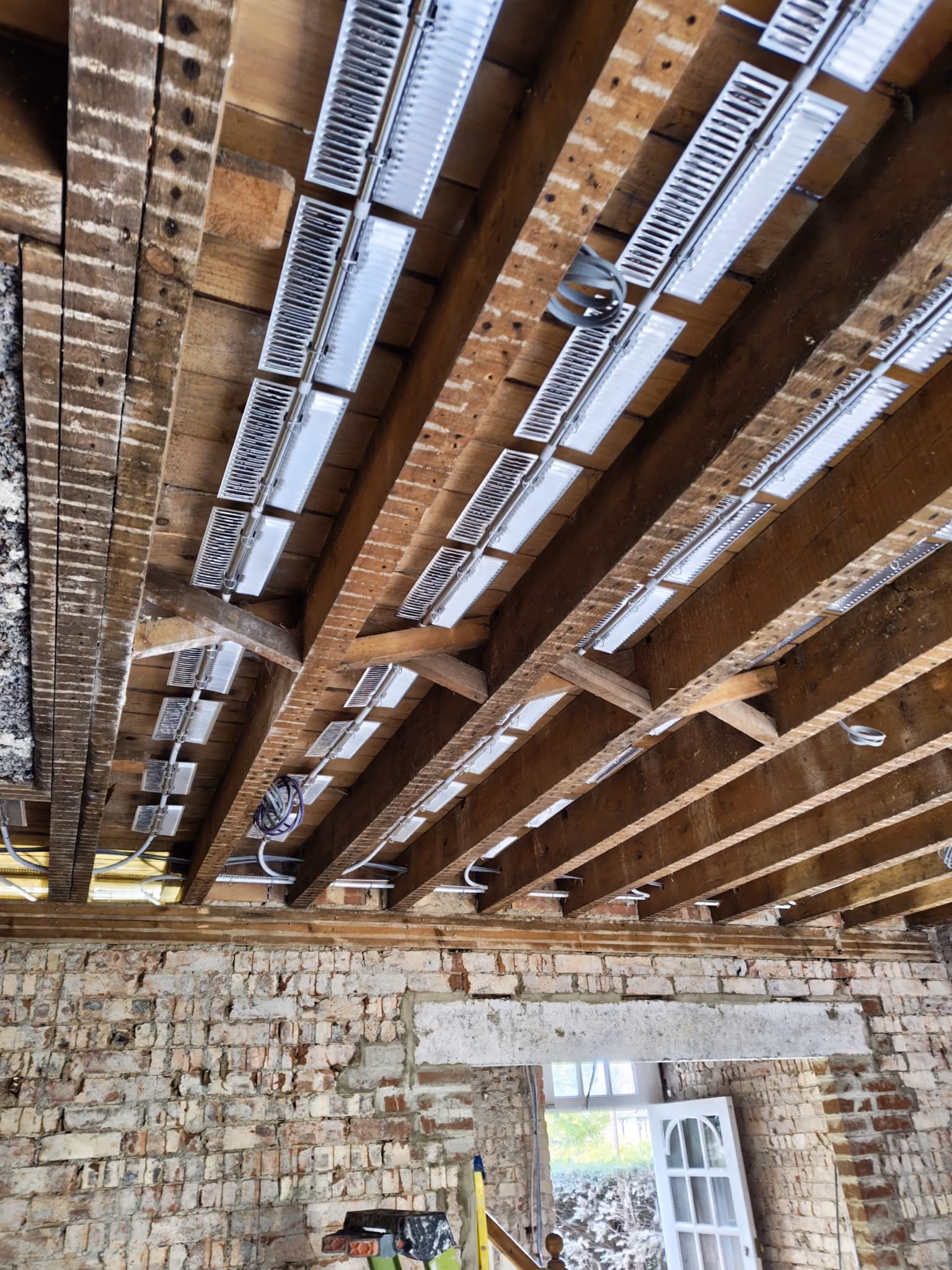 Man installing red radiant floor heating pipes on metallic insulation in modern home.