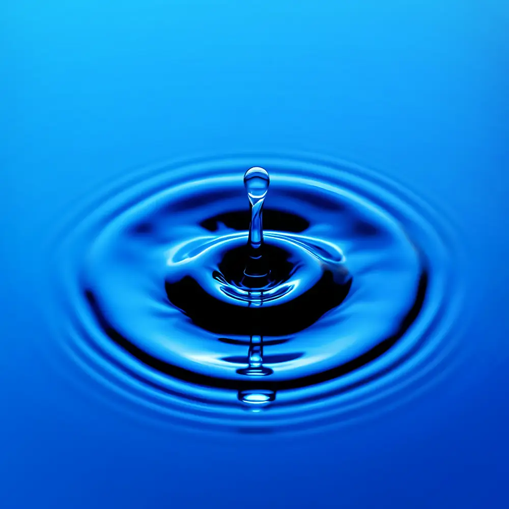 Gota de agua generando ondas circulares sobre una superficie azul.