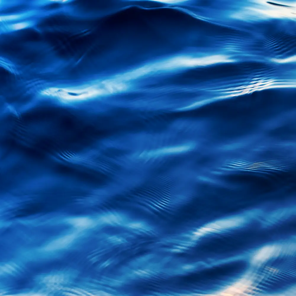 Superficie de agua azul con ondas y reflejos en movimiento.