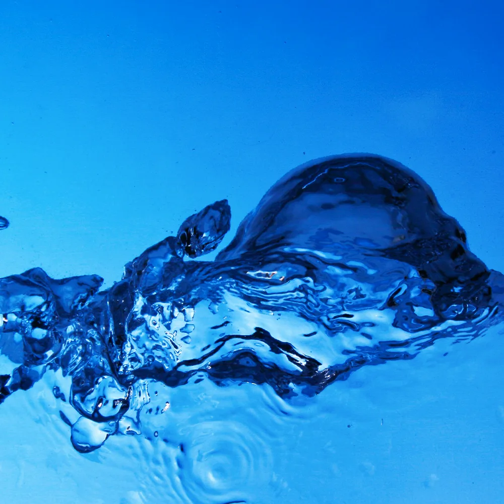 Salpicadura de agua en primer plano sobre fondo azul