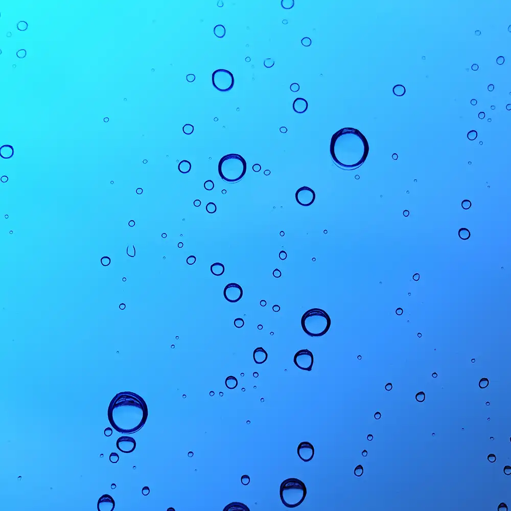 Burbujas suspendidas en agua sobre fondo azul claro