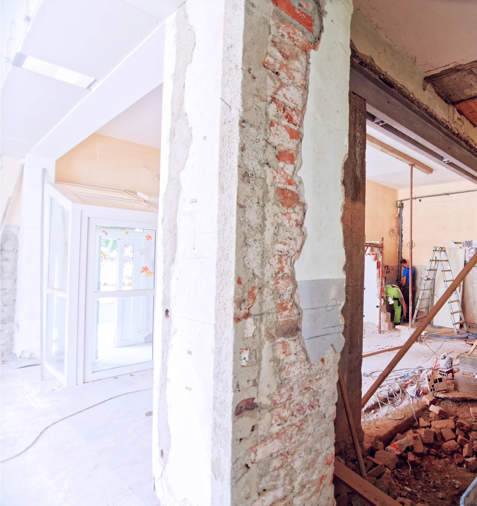 Interior of a building under renovation with exposed brick, construction materials, and workers installing structures.
