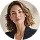 Smiling woman with curly hair wearing a gray blazer over a black top.